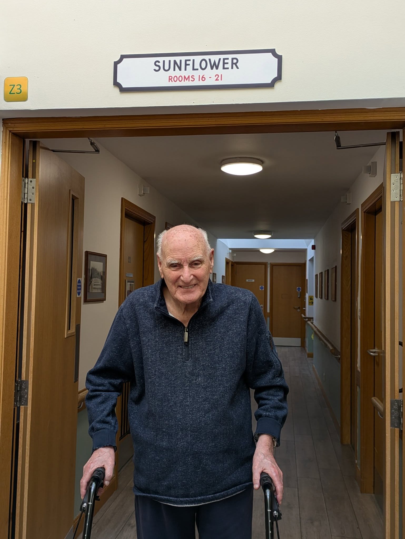 resident standing under a door sign smiling