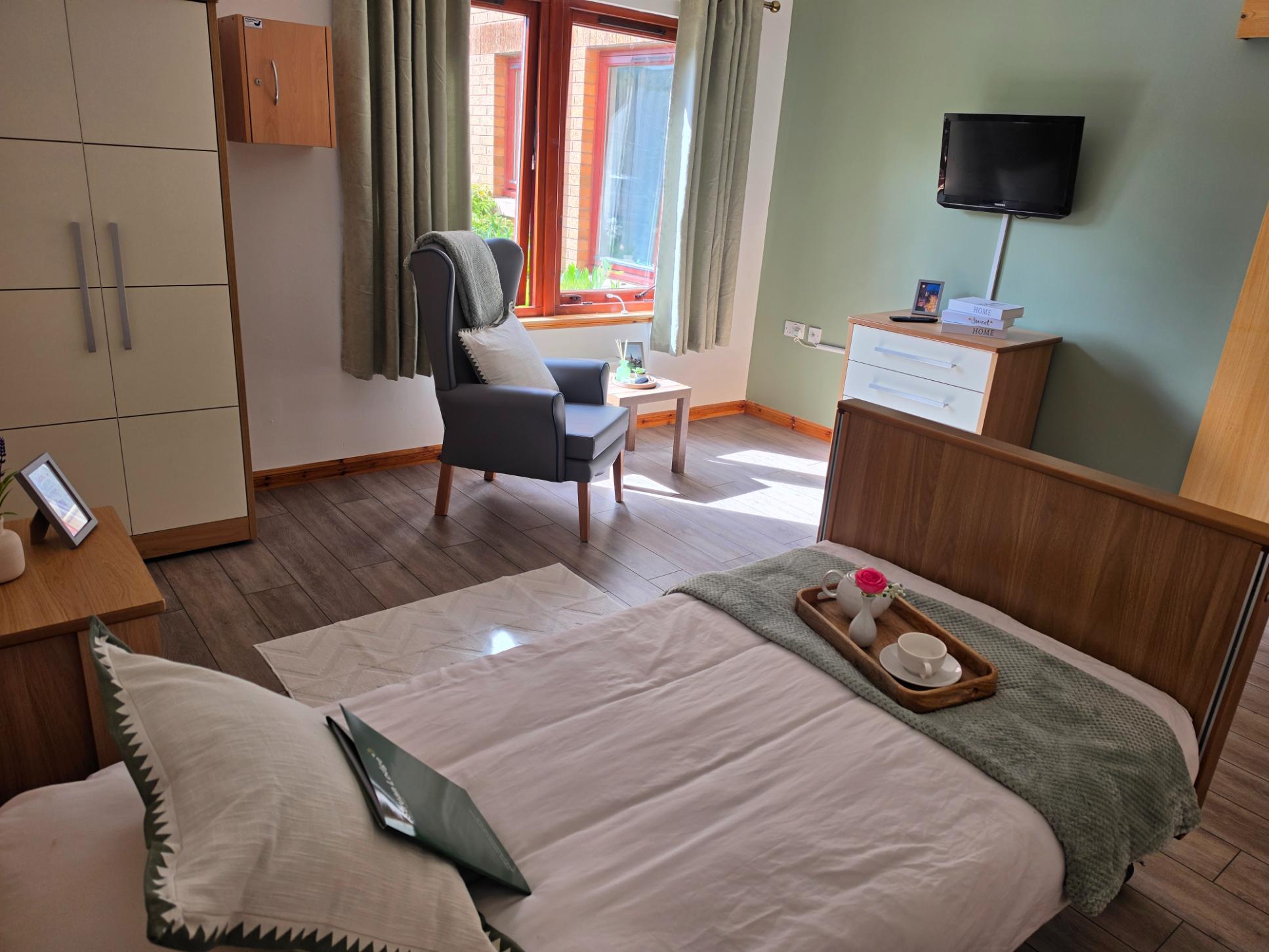 large bedroom with a television, bed and armchairs