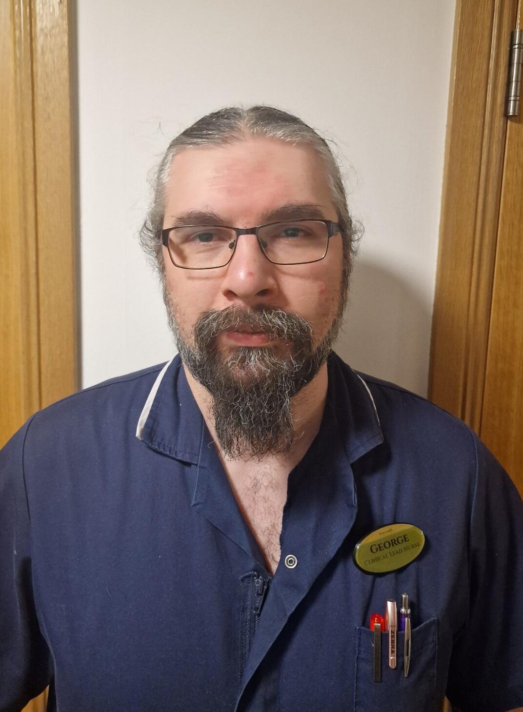 Man with beard in dark purple uniform