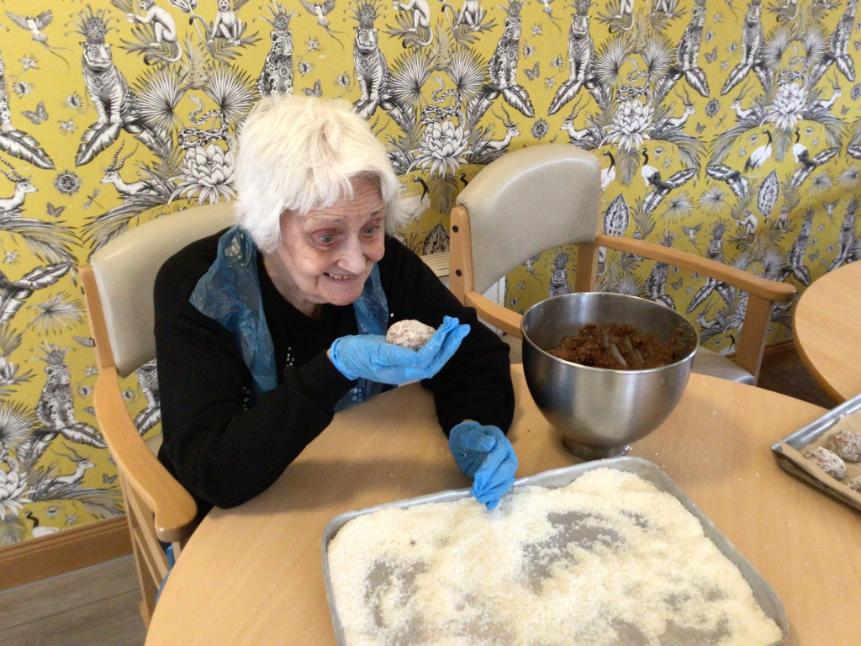 older lady smiling while holding a ball of dough