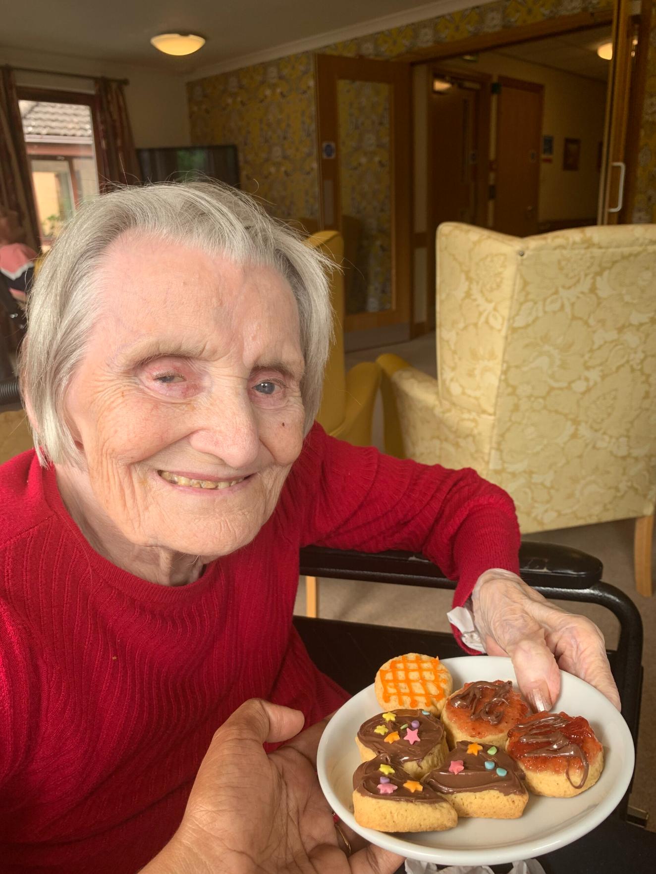 resident smiling with plate of decorated cookies