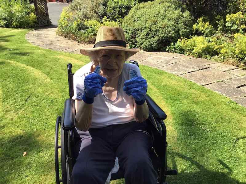 Elderly woman in wheelchair smiling with thumbs up